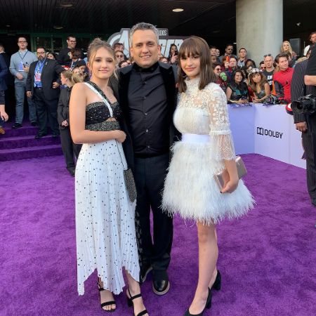 Joe, Ava, and Sophia Russo are posing at the purple carpet for a picture.